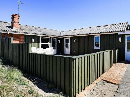 una casa verde con una valla delante en 6 person holiday home in Ringk bing, en Søndervig