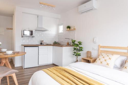 een witte slaapkamer met een bed en een keuken bij Estudio Bianca in L'Escala