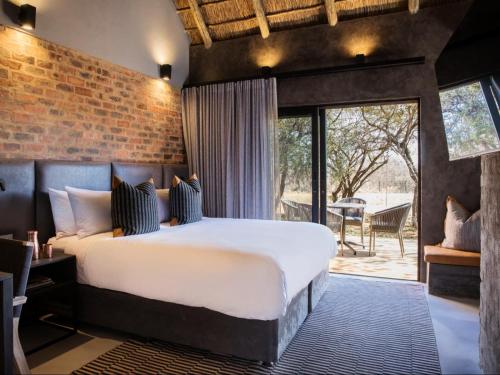 a bedroom with a large bed and a brick wall at NAKO Safari Lodge in Dinokeng Game Reserve