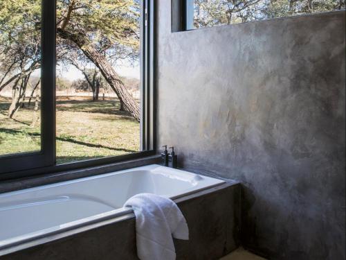 a bath tub in a bathroom with a window at NAKO Safari Lodge in Dinokeng Game Reserve