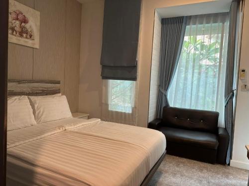 a bedroom with a bed and a chair and a window at BBHOUSE pattaya in Pattaya South
