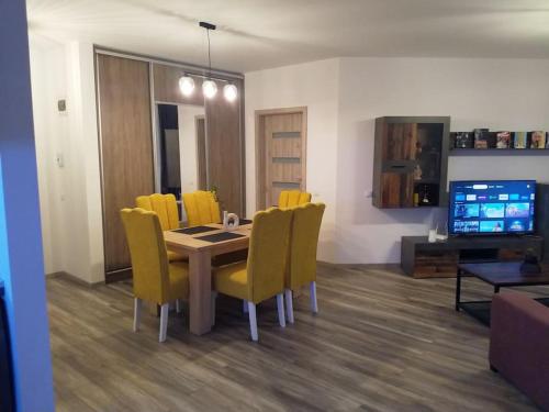 a dining room with a table and yellow chairs at Hightower Apartment in Floreşti