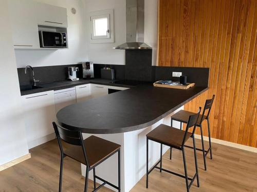 eine Küche mit einer schwarzen Arbeitsplatte und Stühlen in der Unterkunft Appartement au plan d'eau - chez Laurence in Embrun