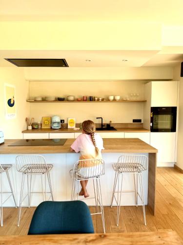 a woman sitting at a counter in a kitchen at Maison Coucou in Thuin