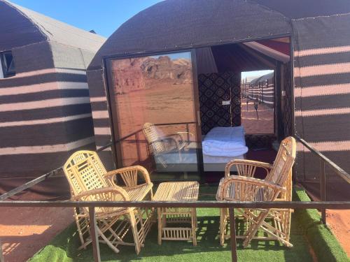 a group of wicker chairs and a table on a patio at Wadi Rum Desert Goals camp in Wadi Rum