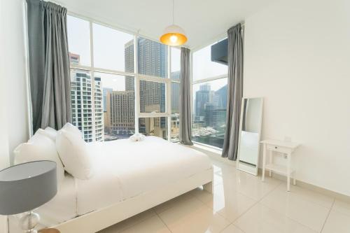 a bedroom with a white bed and a large window at FAM Living - Continental Tower - 2B with Spectacular Marina Views in Dubai
