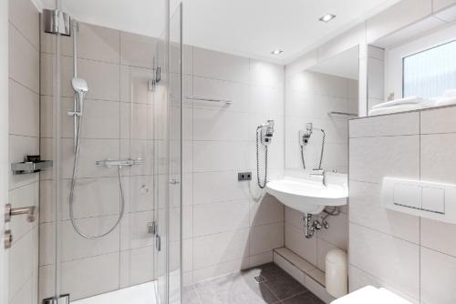 uma casa de banho branca com um chuveiro e um lavatório. em Hotel Restaurant Bismarckturm em Aachen