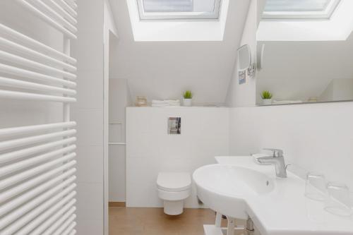 a white bathroom with a toilet and a sink at Yachthafenblick in Heiligenhafen
