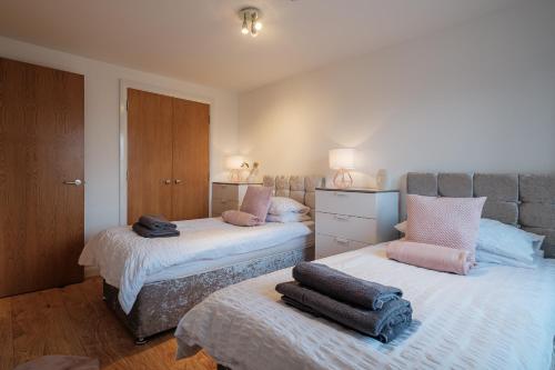 een slaapkamer met 2 bedden en handdoeken bij Mackie Residence - 3 Bed Apartment with parking in Westhill 