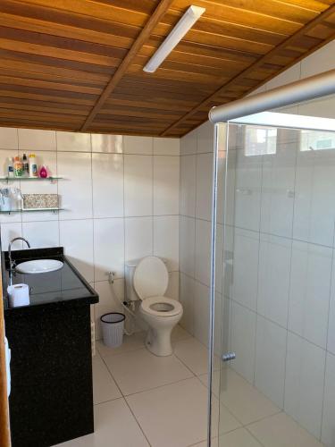 a bathroom with a toilet and a glass shower at Chalé em Maragogi in Maragogi