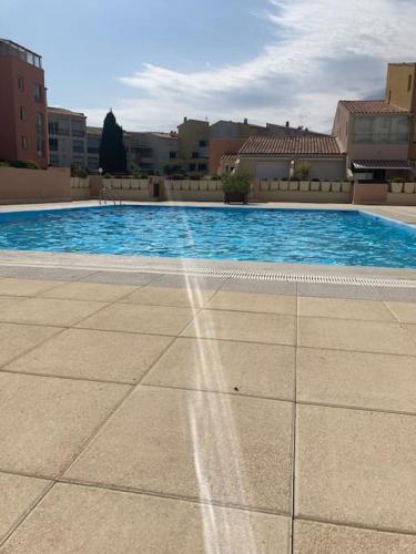 - une piscine d'eau bleue et des bâtiments dans l'établissement Richelieu 4, piscine, parking, port & resto a pied, au Cap d'Agde