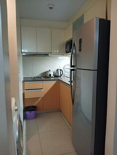a kitchen with a stainless steel refrigerator and wooden cabinets at Mactan Newtown Studio Unit Near Airport in Punta Engaño