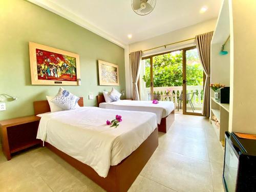 una camera d'albergo con due letti e una televisione di Aman Boutique Hotel a Hoi An