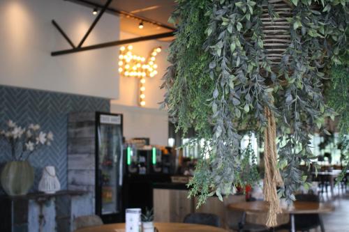 een restaurant met tafels en planten aan het plafond bij HarTeluk Afsluitdijk Zurich in Zurich