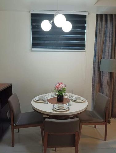 a dining room table with chairs and a table with flowers on it at Mactan Newtown Studio Unit Near Airport in Punta Engaño
