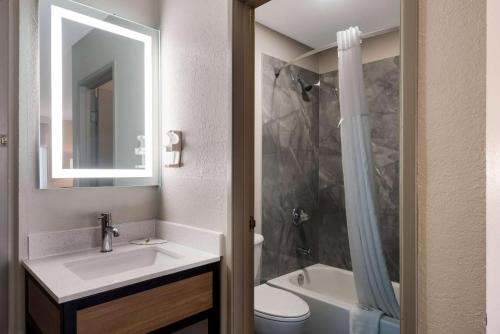 Un baño con lavabo, inodoro y espejo. en Days Inn by Wyndham Ankeny - Des Moines, en Ankeny
