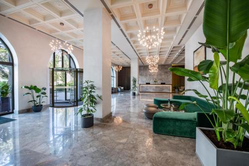 a lobby with a green couch and potted plants at Tbilisi Philharmonic Hotel by Mercure in Tbilisi City