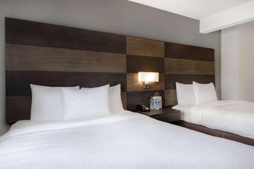 a hotel room with two beds with white pillows at Days Inn by Wyndham Calgary South in Calgary