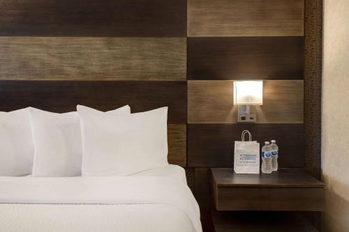 a bed with white pillows and a night stand with two water bottles at Days Inn by Wyndham Calgary South in Calgary