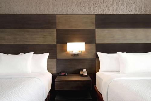 a hotel room with two beds and a phone on a table at Days Inn by Wyndham Calgary South in Calgary