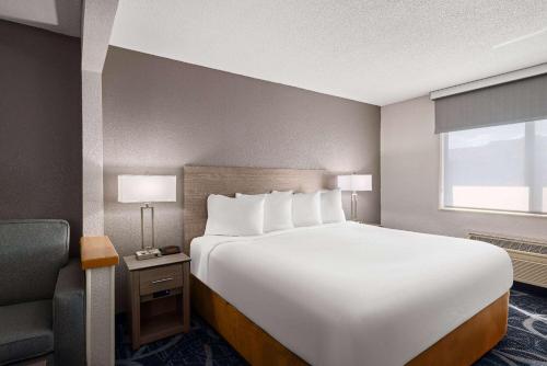 uma grande cama branca num quarto com uma cadeira em Baymont by Wyndham Waterloo em Waterloo