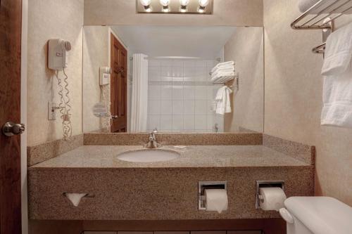 a bathroom with a sink and a mirror at Days Inn by Wyndham Calgary South in Calgary