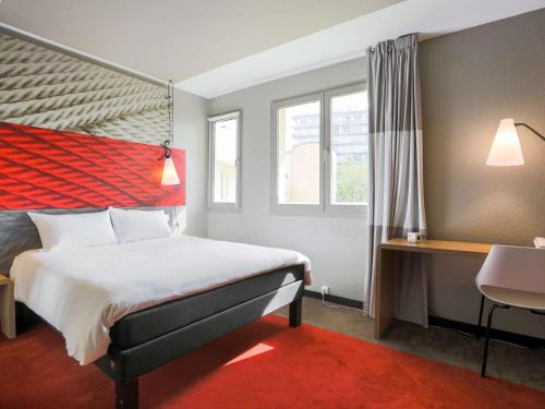 a hotel room with a bed and a window at Ibis Saint Étienne - La Terrasse in Saint-Étienne