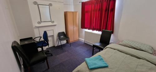 a bedroom with a bed and chairs and a window at Grove Lane in Ipswich