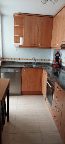 una cocina con armarios de madera y electrodomésticos de acero inoxidable en Costa del Azahar en Torreblanca