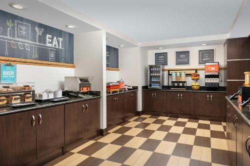 Una cocina de restaurante con gabinetes de madera y piso a cuadros. en Hampton Inn & Suites Lake City, en Lake City