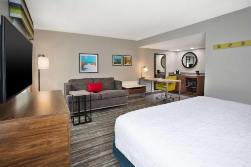Hampton Inn & Suites Cape Coral / Fort Myers في كيب كورال: غرفه فندقيه بسرير واريكه