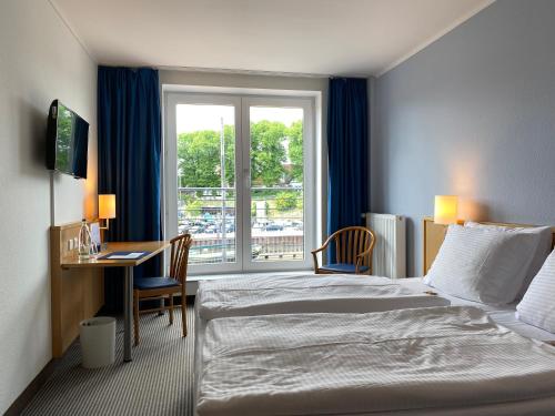 シュターデにあるHotel Stadthafen Stadeのベッド、デスク、窓が備わるホテルルームです。