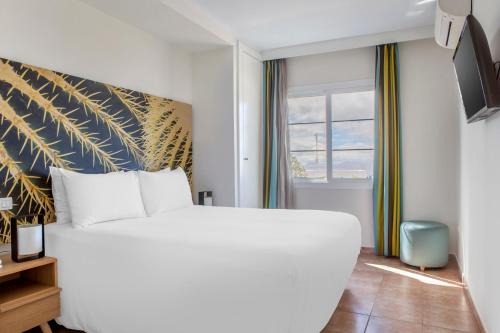 a bedroom with a large white bed and a window at Jardines del Sol in Playa Blanca