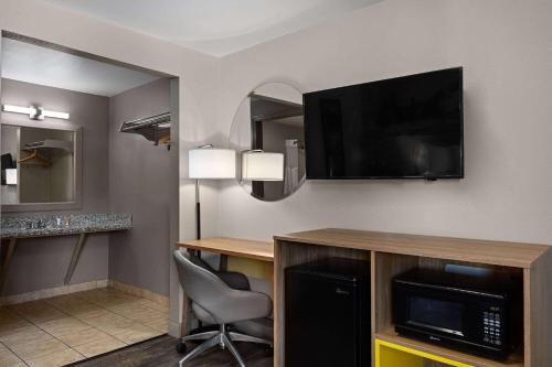 a hotel room with a desk and a flat screen tv at Days Inn by Wyndham Lakewood South Tacoma in Lakewood