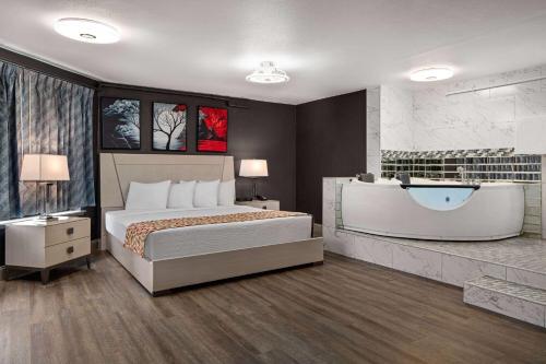 a bedroom with a large bed and a bath tub at Days Inn by Wyndham Lakewood South Tacoma in Lakewood