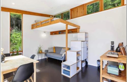 a room with a loft bed and a desk at Fantail’s Nest in the forest in Takaka