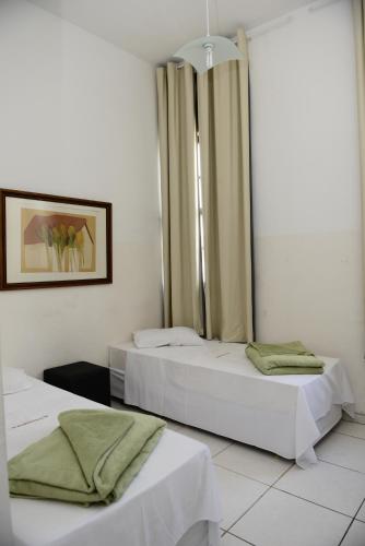 two beds in a room with white walls at Grande Hotel Renascença in Juiz de Fora