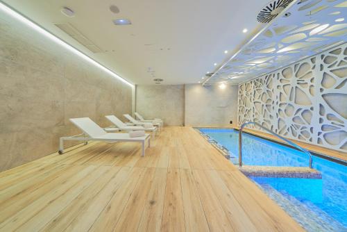 a pool room with white chairs and a swimming pool at Eurostars Oasis Marbella in Marbella