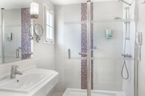 biała łazienka z umywalką i prysznicem w obiekcie Jardines del Sol w mieście Playa Blanca