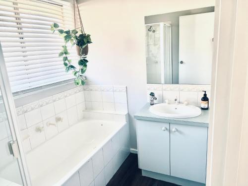een witte badkamer met een bad en een wastafel bij Geelong Bellarine Coastal Stays#Pet Friendly in Clifton Springs