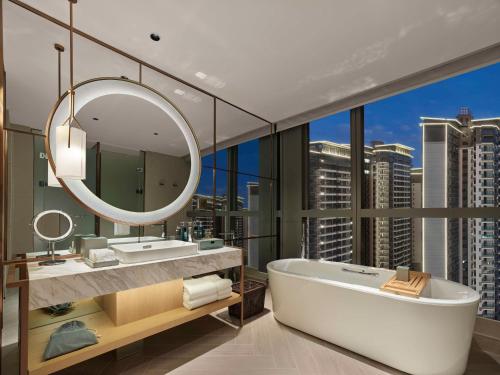 La salle de bains est pourvue d'une baignoire et d'un grand miroir. dans l'établissement Doubletree By Hilton Nanning Wuxiang, à Nanning