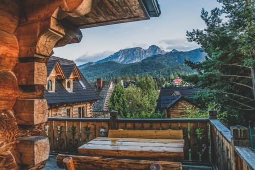 a wooden bench on the balcony of a log cabin at TatryTop Osada Luxury Chalets Kościelisko in Kościelisko