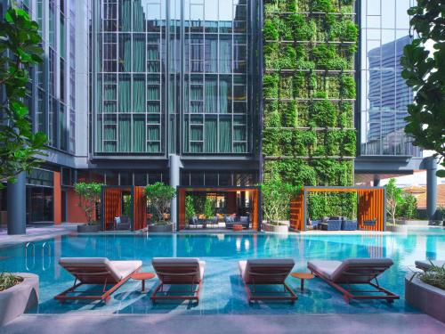 ein großer Pool mit Stühlen und Gebäuden in der Unterkunft Pullman Singapore Hill Street in Singapur