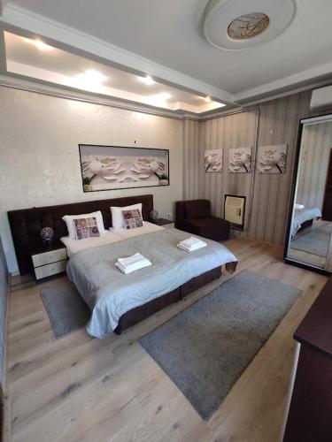 a bedroom with a large bed and a chair at Apart Club Tolstogo in Chernivtsi