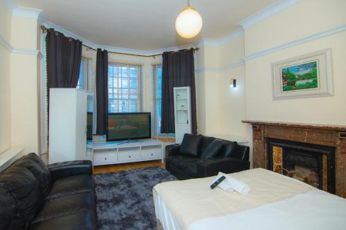 ロンドンにあるVictorian Woods BnBのベッドとテレビが備わるホテルルームです。