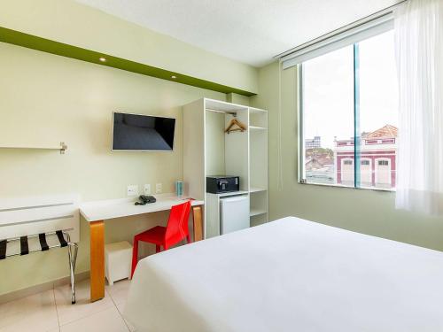 Habitación de hotel con cama, escritorio y ventana en ibis Styles Manaus, en Manaus