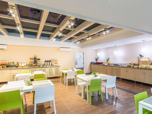 a restaurant with white tables and green chairs at ibis Styles Manaus in Manaus