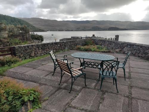 a table and chairs sitting next to a lake at Melfort Pier & Harbour Resort in Kilmelfort