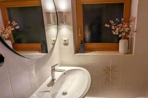 La salle de bains est pourvue d'un lavabo, d'un miroir et de fleurs. dans l'établissement großes Berg-Chalet in der Natur, à Bayrischzell