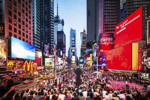 a crowd of people walking down a busy city street at voco Times Square South New York by IHG in New York
